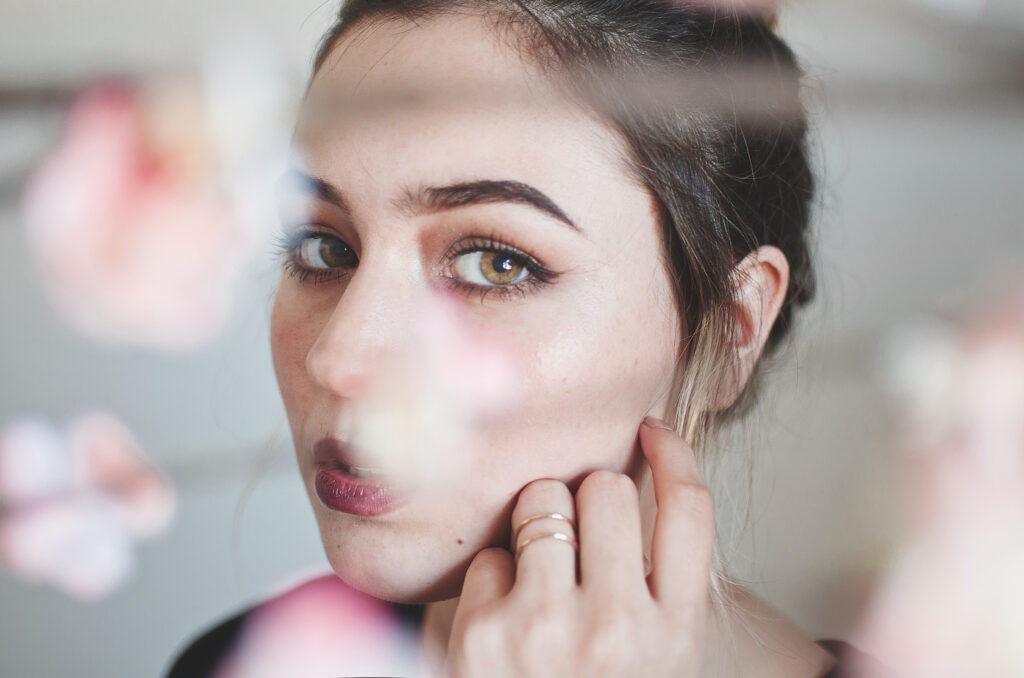Darian Rojas's portrait captures a close-up of a person's face framed by delicate pink flowers with a focus on the eyes and lips.
